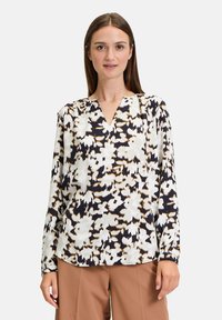 Langärmlige Bluse mit V-Ausschnitt, die ein florales Muster in Schwarz, Weiß und Beige auf einem hellen Hintergrund zeigt. Glattes Material und lockere Passform.