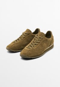 Brune ruskind sneakers med afrundede tæer, teksturerede overdele og snørebåndslukninger. Med en subtil kontraststribe på sålen.