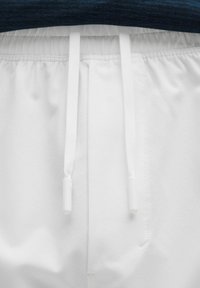 Pantalones de chándal blancos con una cinturilla elástica y dos cordones blancos. La tela es suave con un ligero brillo.