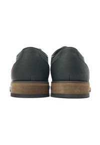 Black leather shoes with a textured finish, featuring a wooden heel and a flat sole. The design is simple and classic without embellishments.