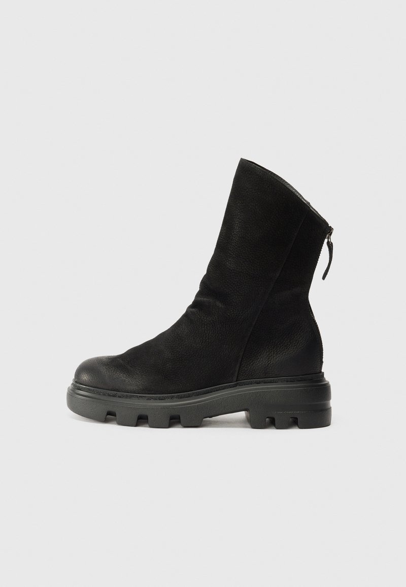 Botte en cuir noire mi-mollet avec semelle en caoutchouc épaisse, bout rond, et tirette de fermeture éclair à l'arrière, montrée de profil sur un fond uni.