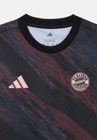 Svart fotballdrakt med abstrakt rød og blå gradientdesign, med Adidas-logo i rosa og FC Bayern München-emblemet foran.
