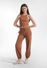 Brązowy, prążkowany krótki top z okrągłym dekoltem, zestawiony z dopasowanymi, luźnymi spodniami z elastycznym pasem i mankietami.