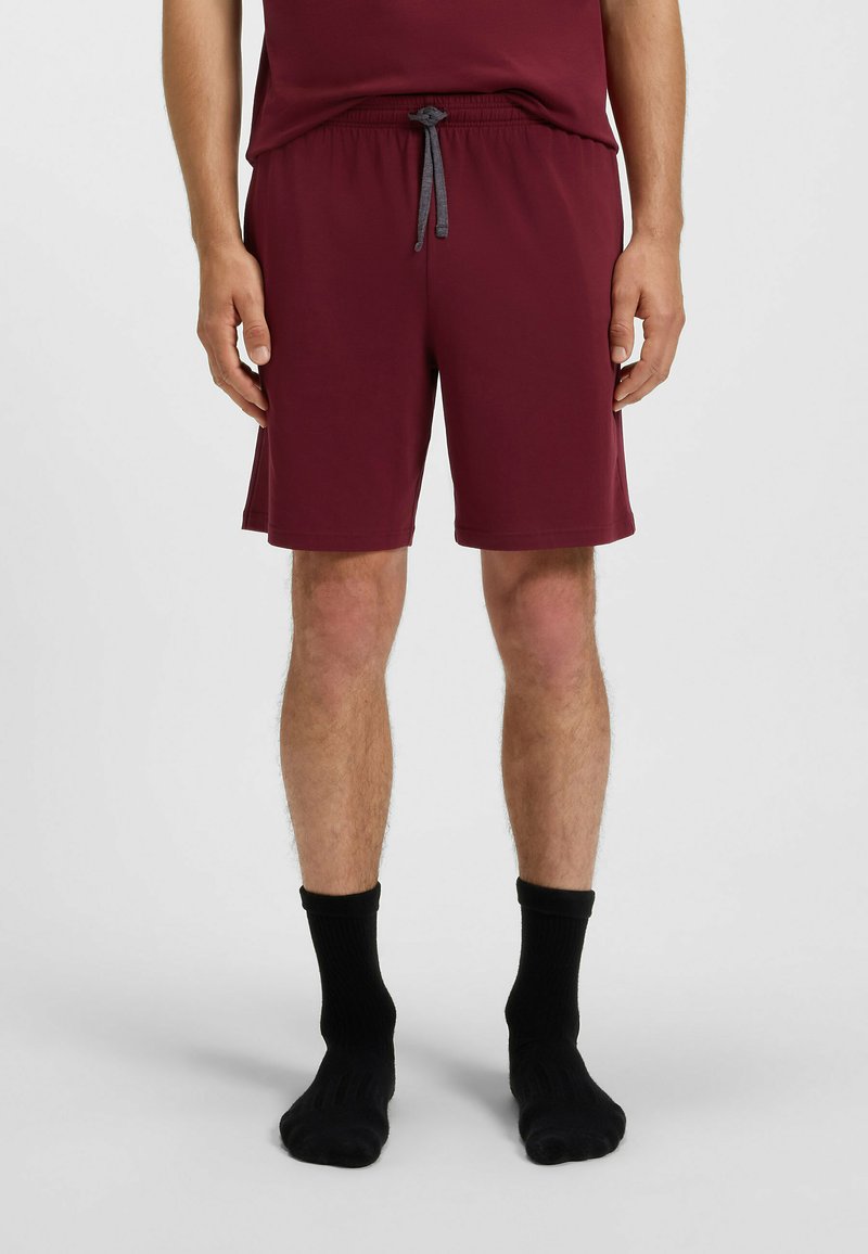Burgundy shorts med elastisk midjeband och grå dragsko, med en mjuk textur och en avslappnad passform, i kombination med svarta strumpor.