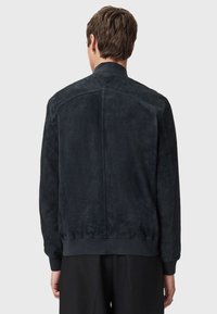 Giacca bomber in suede scuro con cintura aderente, polsini a coste e un design del colletto semplice, che mette in mostra una texture liscia e opaca.