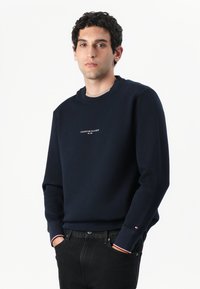 Sweatshirt azul-marinho feito de mistura de algodão, com decote redondo e punhos canelados com detalhes em vermelho e branco. logotipo no peito.