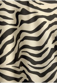 Zebra-gepatroneerde stof met glanzende zwarte en beige strepen, met een gladde textuur en golvende lijnen die dynamische visuele interesse creëren.