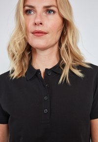 Sort polo skjorte med knaplukning og korte ærmer, lavet af tekstureret stof. Glat overflade med klassisk kravedesign.