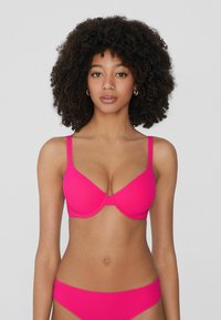 Světlý růžový bikinový set s tvarovanou podprsenkou a nastavitelnými ramínky, doplněný o odpovídající vysoké kalhotky, obojí vyrobené z hladkého a pružného materiálu.