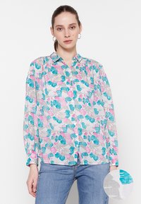 Bloes met bloemenprint, gemaakt van een lichtgewicht, gestructureerde stof met roze en teal patronen, lange mouwen en een kraag.