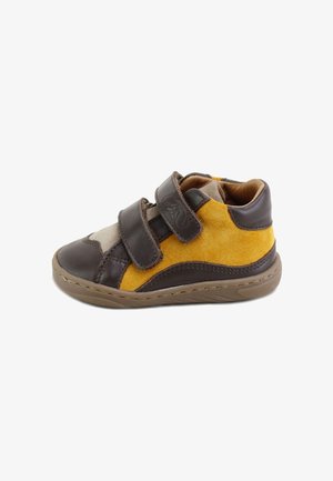 Zapato infantil en marrón y amarillo con materiales de ante y cuero, con dos tiras ajustables de velcro y suela de goma con patrón texturizado.