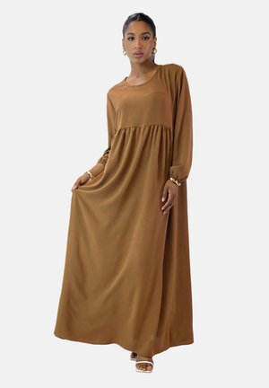 Robe maxi longue marron en tissu doux, avec un col rond, des manches longues et une taille froncée, créant une silhouette fluide.