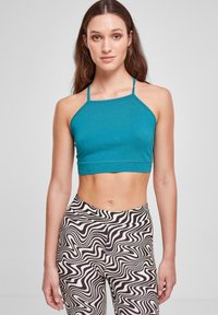 Petrolfarvet crop top med tynde stropper og lige halsudskæring, parret med højtaljede leggings i sort og hvidt svulmønster.