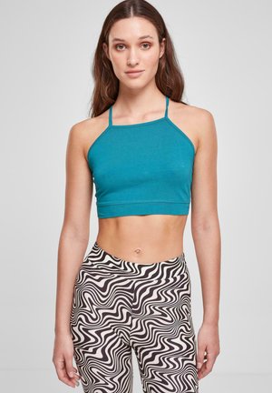 Petrolfarvet crop top med tynde stropper og lige halsudskæring, parret med højtaljede leggings i sort og hvidt svulmønster.