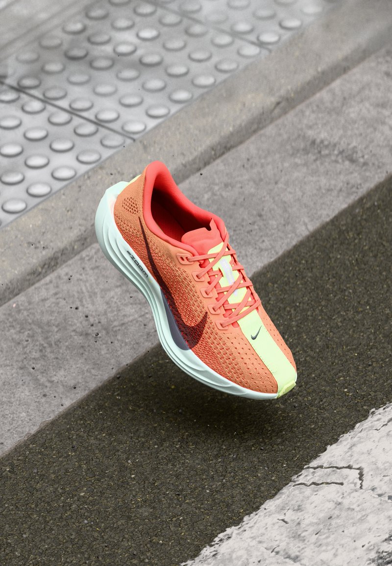 Běžecká obuv Nike v růžové a neonově zelené barvě, s textilním svrškem, polstrovaným límcem, strukturovanou podešví a velkým logem swoosh.