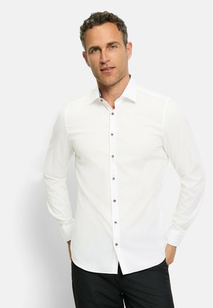 Weißes Langarmhemd mit Button-Down-Kragen und braunen Knöpfen. Verfügt über eine glatte Textur und eine figurbetonte Passform. Trägt dazu eine schwarze Hose.
