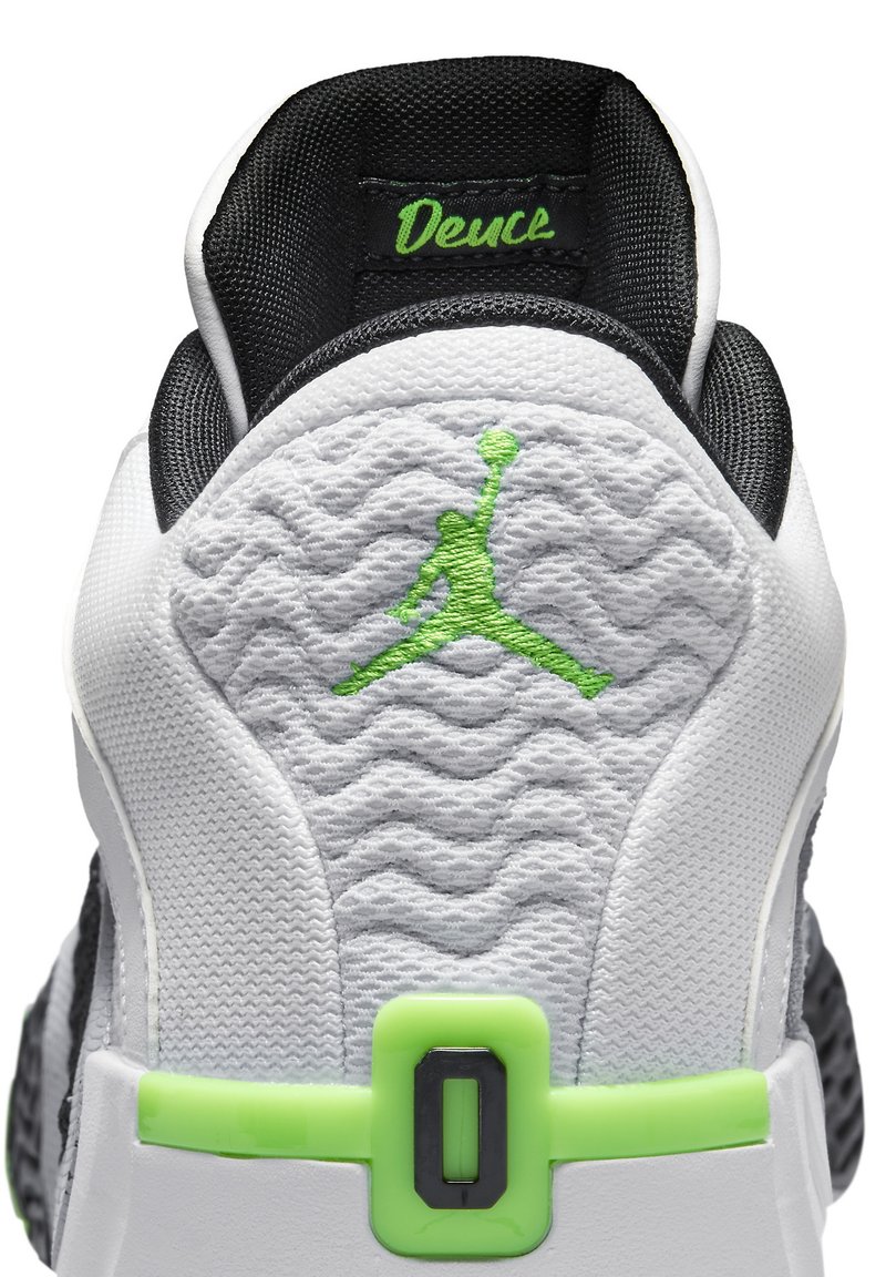 Zapatilla blanca y negra con un upper texturizado, acentos verdes y un destacado logo de Jordan en la parte trasera. Presenta un detalle de correa de bloqueo.