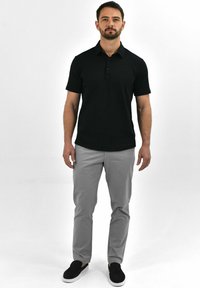 Black short-sleeve polo shirt, grey slim-fit trousers, and black slip-on shoes. Simple design with no patterns or hardware details.