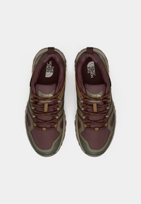 Zapatos de senderismo en color granate y verde oliva con tejido texturizado, punteras reforzadas y cordones marrones; cuentan con un logo en la plantilla y una lengüeta en el talón.