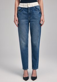 Jeans de denim en un tono azul claro, con una cinturilla blanca, diseño de pierna recta, cinco bolsillos y un sutil efecto de desteñido en la tela.