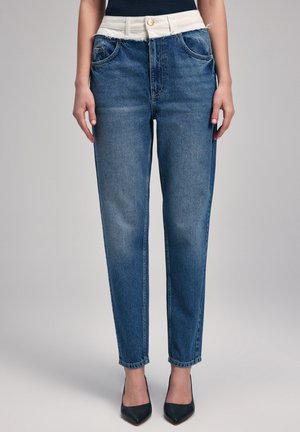 Denim jeans with a light blue hue, featuring a white waistband, straight leg design, five pockets, and subtle whiskering on the fabric.