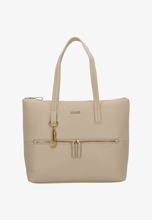 Sac cabas en cuir beige avec deux poignées supérieures, poche zippée à l'avant, quincaillerie dorée et détails du logo. Texture lisse avec un design minimaliste.