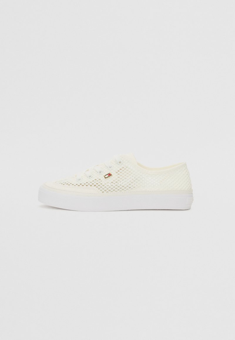 White mesh sneakers with a flat rubber sole, featuring round laces and a small logo accent on the side. Breathable design for comfort.