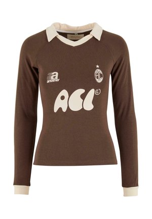 Camisa de manga larga marrón con un cuello y puños blancos, que presenta un gran logotipo blanco y un pequeño emblema en el pecho. Material de algodón suave.