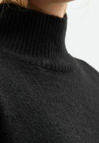 Schwarzer Rollkragenpullover aus strukturiertem Strickstoff, mit einem gerippten Kragen und einem glatten Körper, ideal zum Schichten.