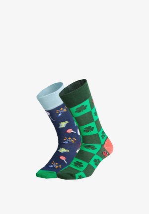 Chaussettes avec un design bleu orné de motifs colorés de cadeaux et de bonbons sur l'une, et un motif à carreaux verts avec des trèfles sur l'autre.
