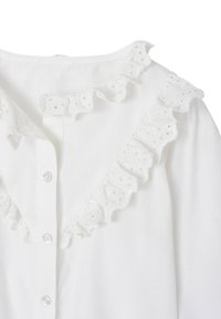 White shirt with a button closure, featuring a ruffled collar adorned with eyelet patterns. The fabric appears soft and lightweight.