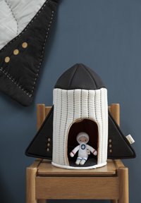 Plišasta igrača v obliki rakete iz črnega in belega blaga z všitimi detajli, z majhno astronautko v rjavi notranjosti.