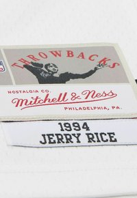 Throwbacks-Label mit einer Grafik eines vintage Fußballspielers, "Mitchell & Ness Philadelphia" Branding und dem gestickten Text "1994 Jerry Rice".