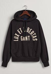 Černá mikina s kapucí a klokaní kapsou, s krémovým textem "LUX ET LIBERTAS GANT" umístěným na přední straně a ribováním na rukávech.
