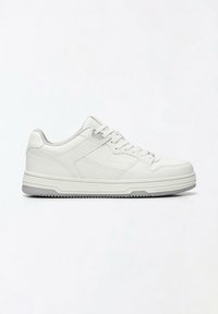 Baskets basses blanches avec système de lacets, col rembourré, et semelle texturée, présentées en profil droit sur un fond uni.