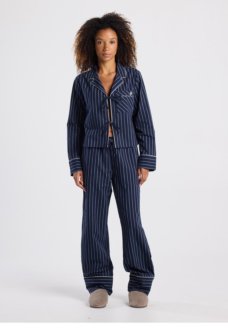 Navy striped pajama set featuring a tie-front jacket with a notched collar and matching pants with a loose fit and white accents.