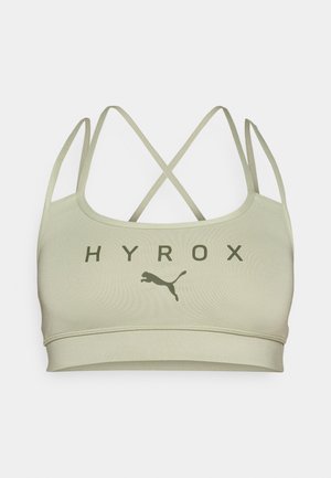 Világos olíva zöld sportmelltartó, keresztpántos kivitelben, a "HYROX" felirattal és sötétzöld Puma logóval. Sima tapintású és rugalmas anyag.
