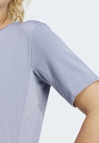 Lichtblauw kort mouwtopje van gladde stof met een ronde halslijn en subtiele stikseldetails langs de naden.