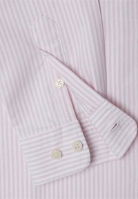 Světle růžová bavlněná košile s úzkými bílými pruhy, obsahující manžetu na knoflíky a límec ve tvaru cutaway. Dokončovací detaily zahrnují bílé knoflíky.