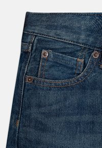 Dunkelblaue Jeans aus Denim mit geradem Schnitt, ausgestattet mit Kupferriegeln, einer kleinen Vordertasche und kontrastierenden Nähten an den Säumen.
