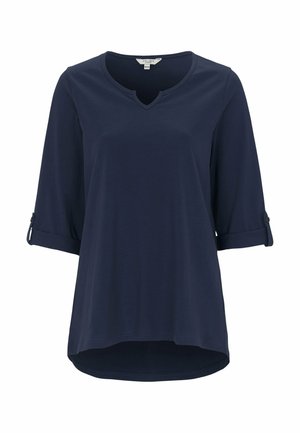 Marinblus, lättviktig med V-ringning, trekvartslånga ärmar och rull-tab-kuffar. Slät textur med en rundad fåll.