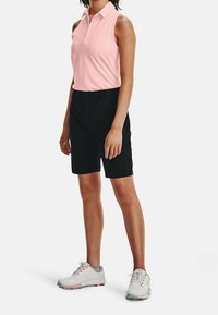 Light pink sleeveless polo shirt, paired with black shorts. Footwear is gray with red accents. Fabrics appear smooth and flexible.