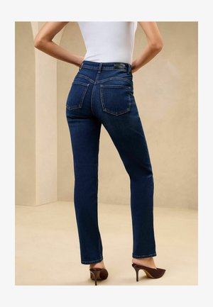 Tumedad sinisid liibuv must nahk, sirge jalg ja tagataskud. Omab peent õmblust ja nahast vöökleebist.