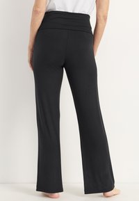 Zwarte, wijde broek met een brede, gevouwen tailleband. Gemaakt van zachte stof, met een gladde textuur en een ontwerp tot de enkel.