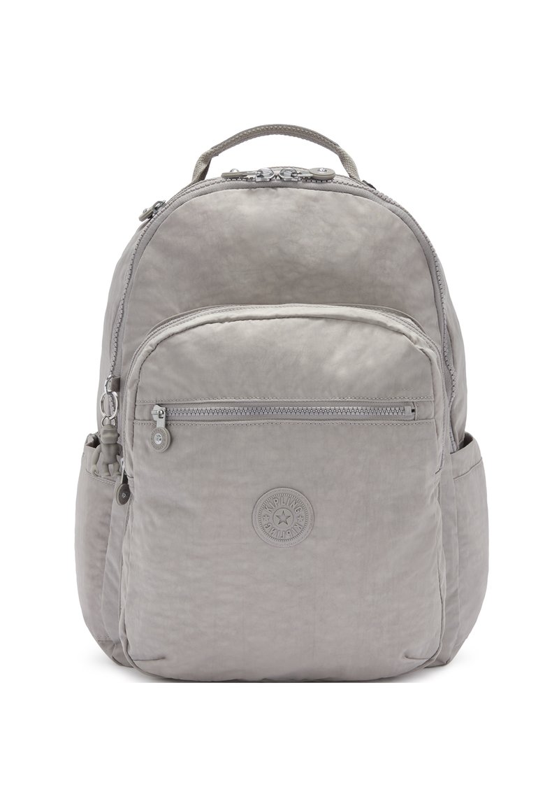 Mochila gris claro con tela texturizada, cremalleras suaves, bolsillo frontal con cremallera, bolsillos laterales de malla y un parche de logo circular.