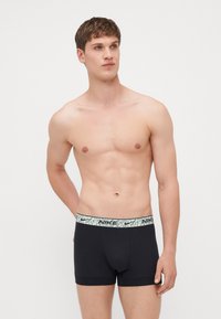 Black boxer briefs with an elastic waistband featuring a light-patterned design and Nike logo. Made from stretchy, smooth fabric.