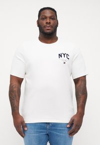 Biele tričko s krátkymi rukávmi, na prsiach s námořníckou NYC logom. Vyrobené z hladkej bavlnenej látky s okrúhlym výstrihom a klasickým strihom.