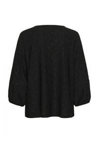 Blouse noire à coupe ample, manches longues bouffantes, avec broderies délicates et détails ajourés. Tissu doux avec un motif texturé.