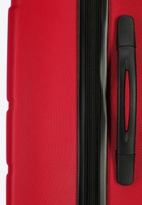 Roter Hartschalenkoffer mit einer strukturierten Oberfläche, schwarzem Reißverschluss und Griff. Verfügt über ein schlankes, rechteckiges Design für einfachen Transport.