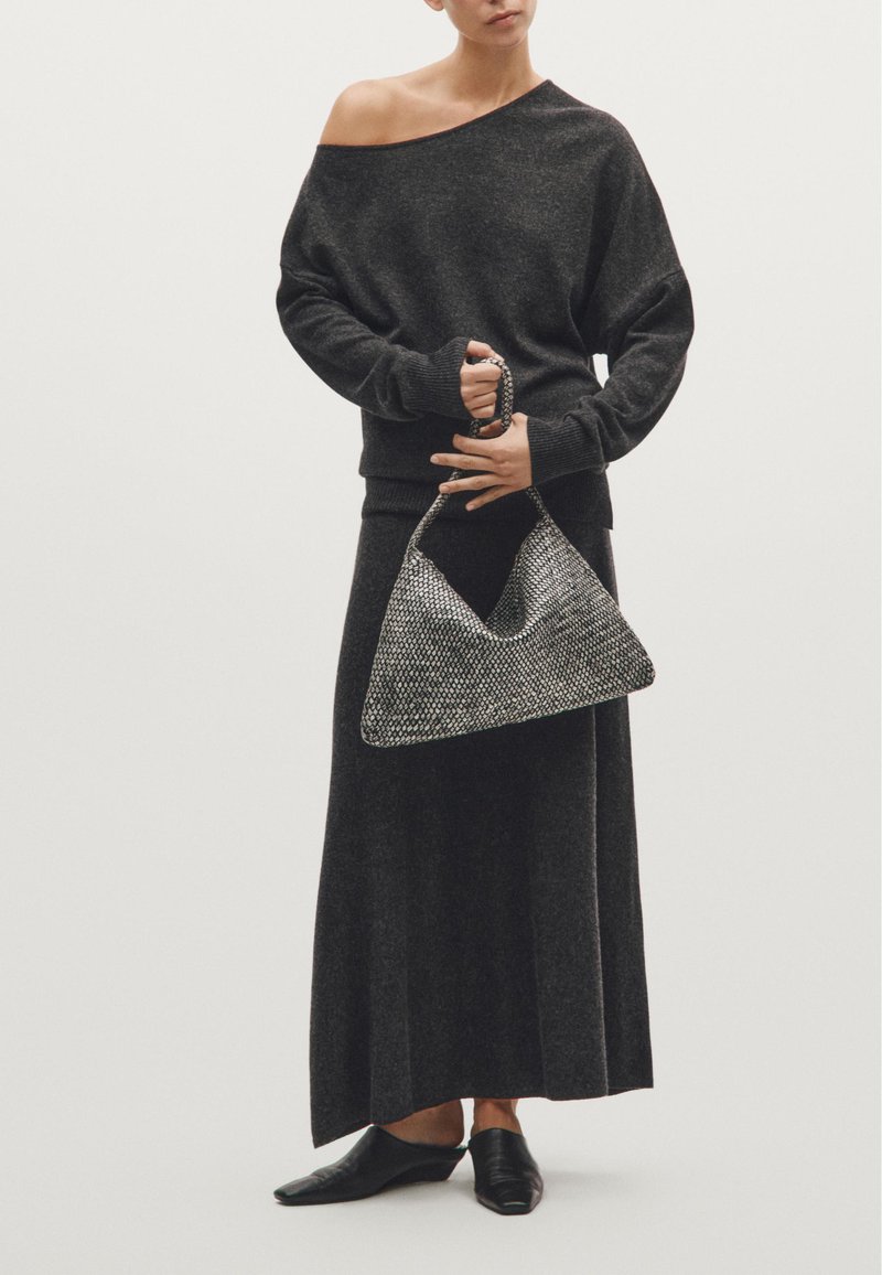 Szary dzianinowy sweter na jedno ramię i długa spódnica, połączone z torebką w metaliczny wzór i czarnymi butami na szpilkach. Gładkie tekstury w całej stylizacji.